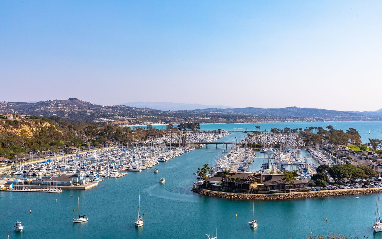 Dana Point Harbor marina filled with boats, with coastal hills along the horizon.