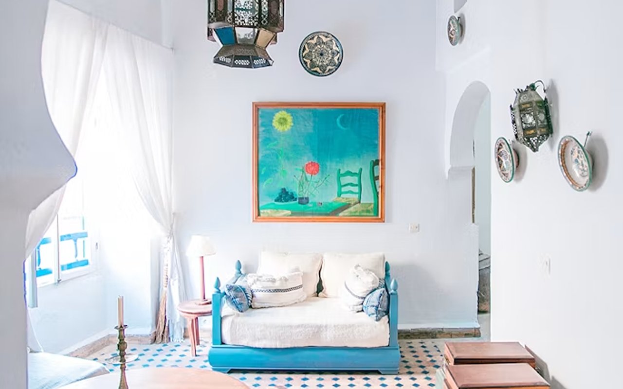 Bright living room with a turquoise-framed sofa, patterned tile floor, and colorful wall art.