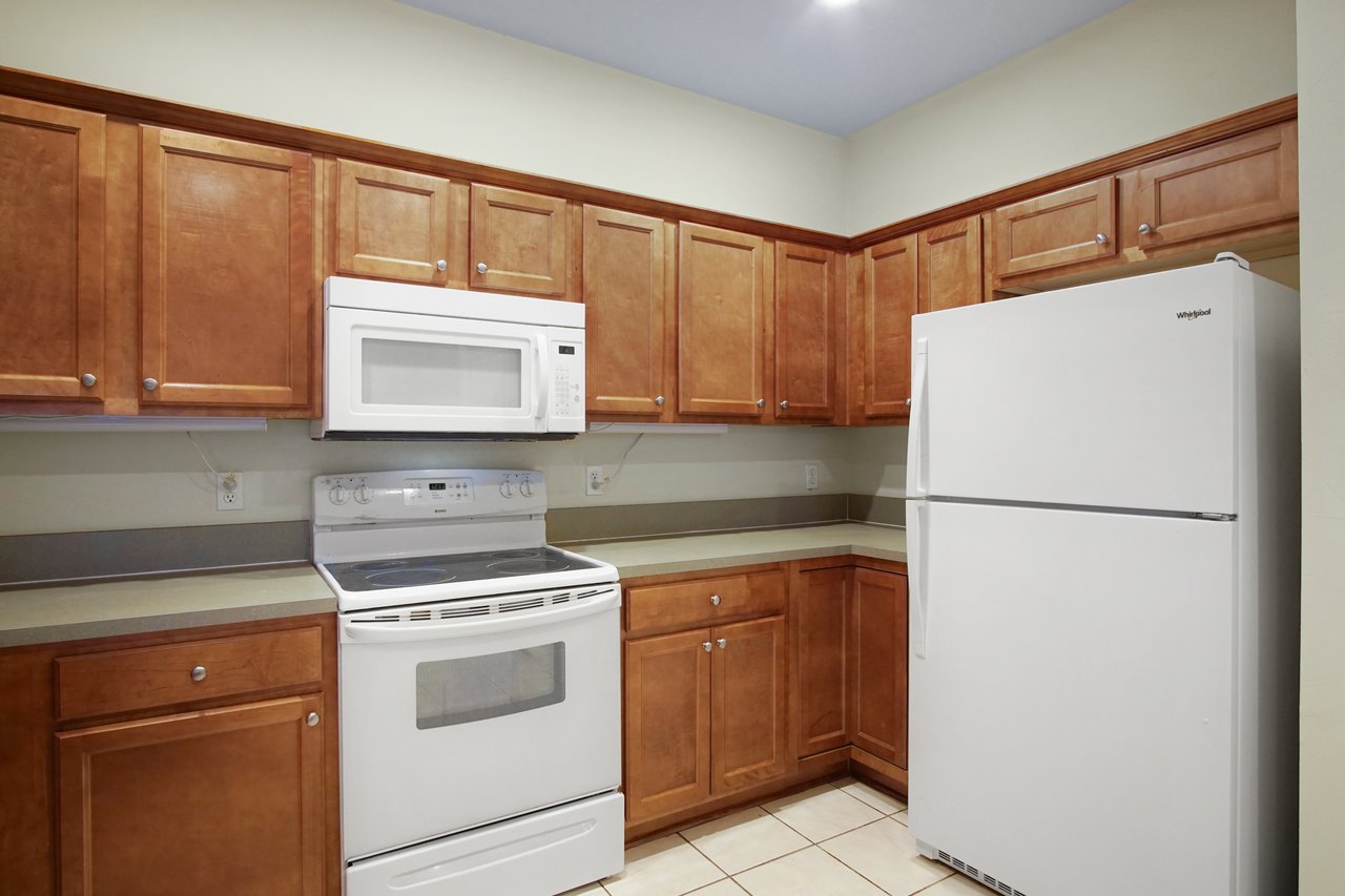 Kitchen at 5441 Hampton Hill Circle, Tallahassee, Florida 32311 featuring wood cabinetry, white appliances, and tiled flooring.