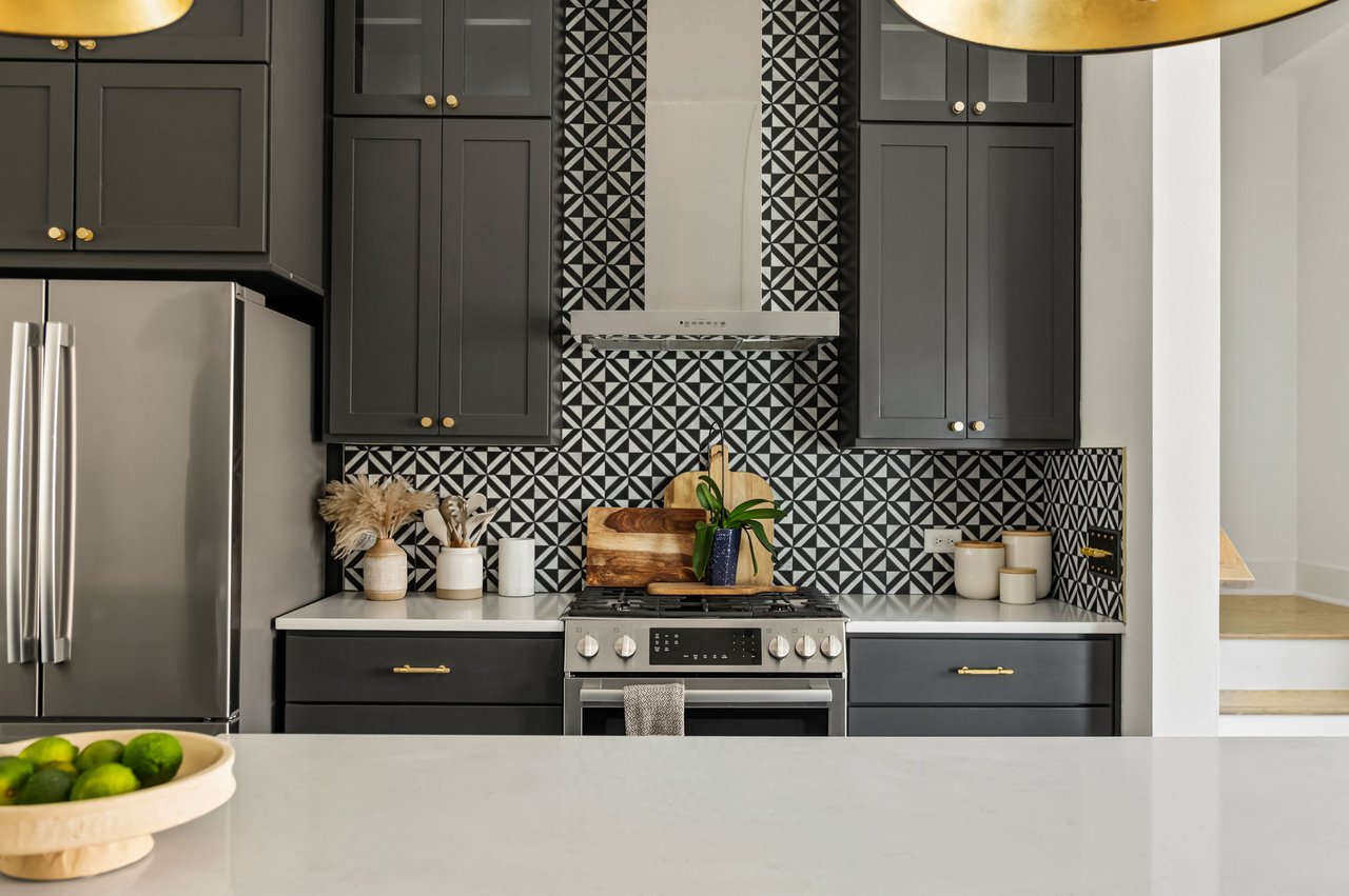 Kitchen detail at 4507 Unity Circle in The Grove, Austin, with charcoal cabinetry, a marble mosaic backsplash, and stainless steel range, upgrades by Ashley Walker Designs.
