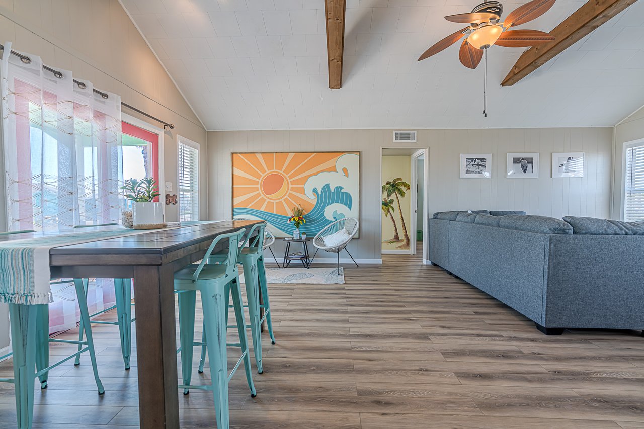 Open Living Space with wood table with teal chairs and a gray L Shaped Sofa, Presented by Cathy Carter, REALTOR Carter Signature Properties.