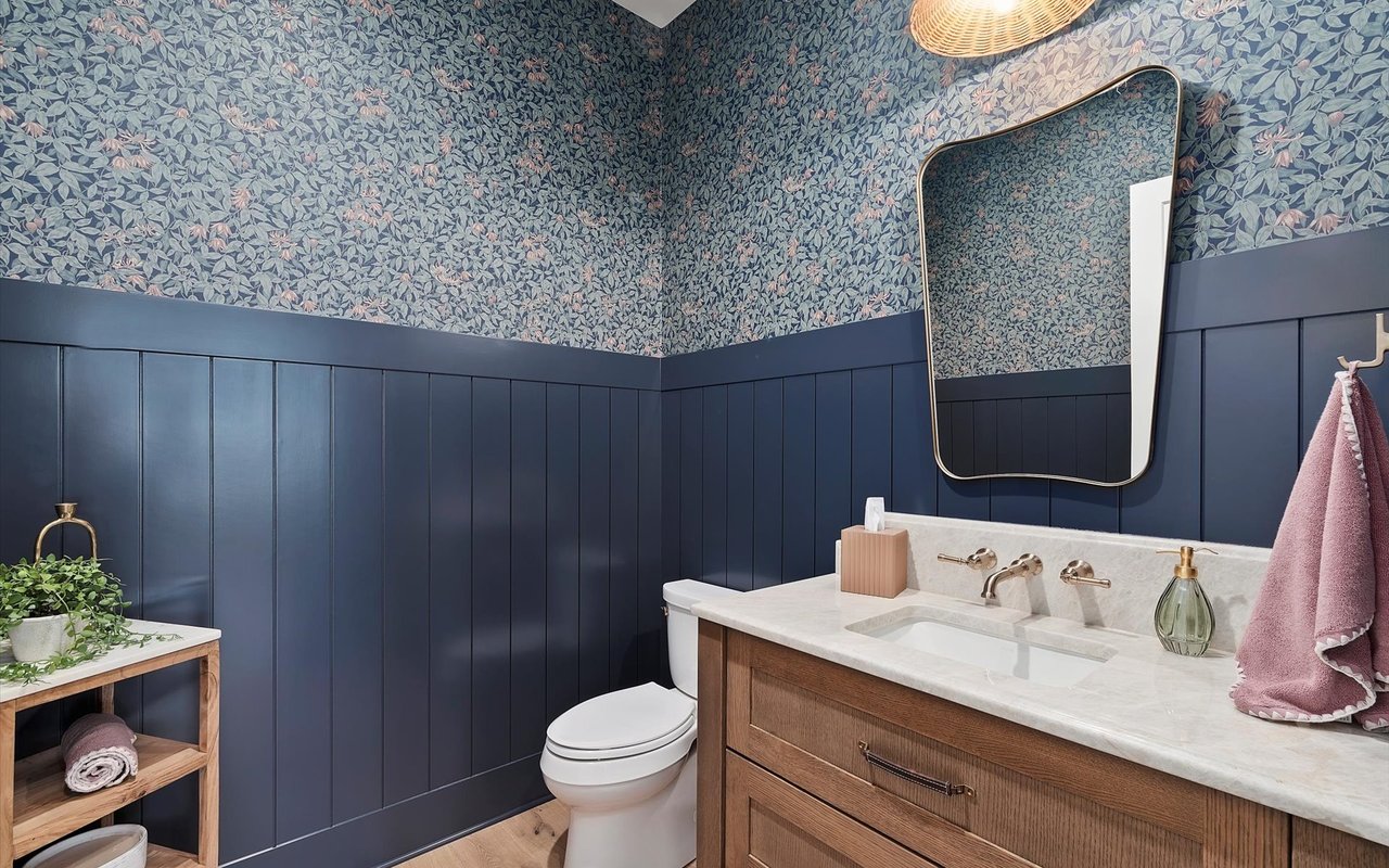 Powder room featuring dark blue beadbord wainscotting and blue, green and pink floral wallpaper