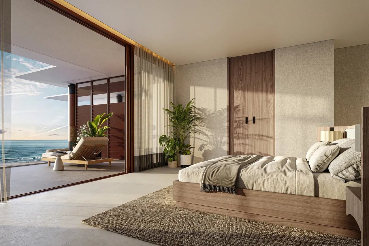 Modern bedroom with a platform bed and ocean views through open glass doors.