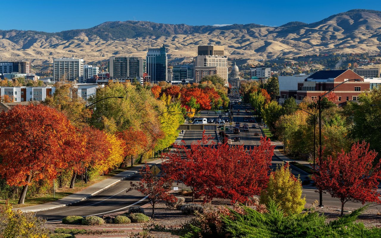 Downtown Boise framed by colorful autumn trees, with foothills behind the skyline.