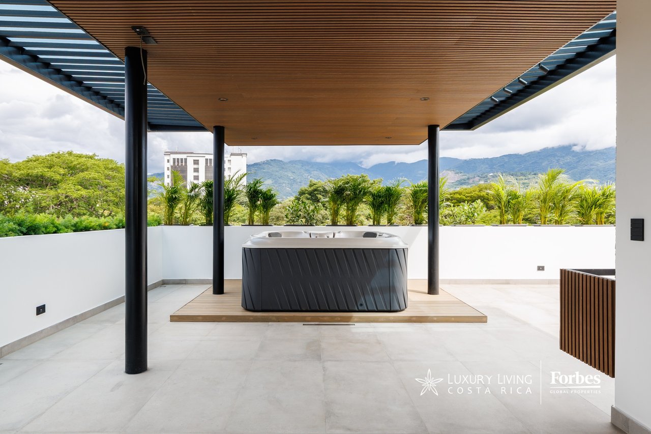 Rooftop terrace with a covered jacuzzi, mountain views, and a wood-slat canopy.