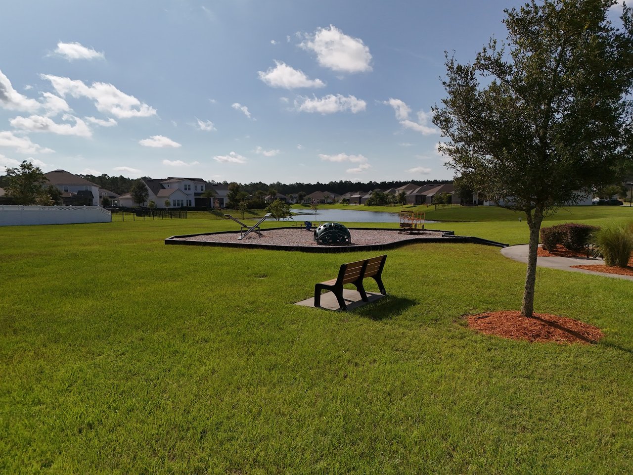 Silverleaf Village park with a small playground, bench, and pond among surrounding homes.