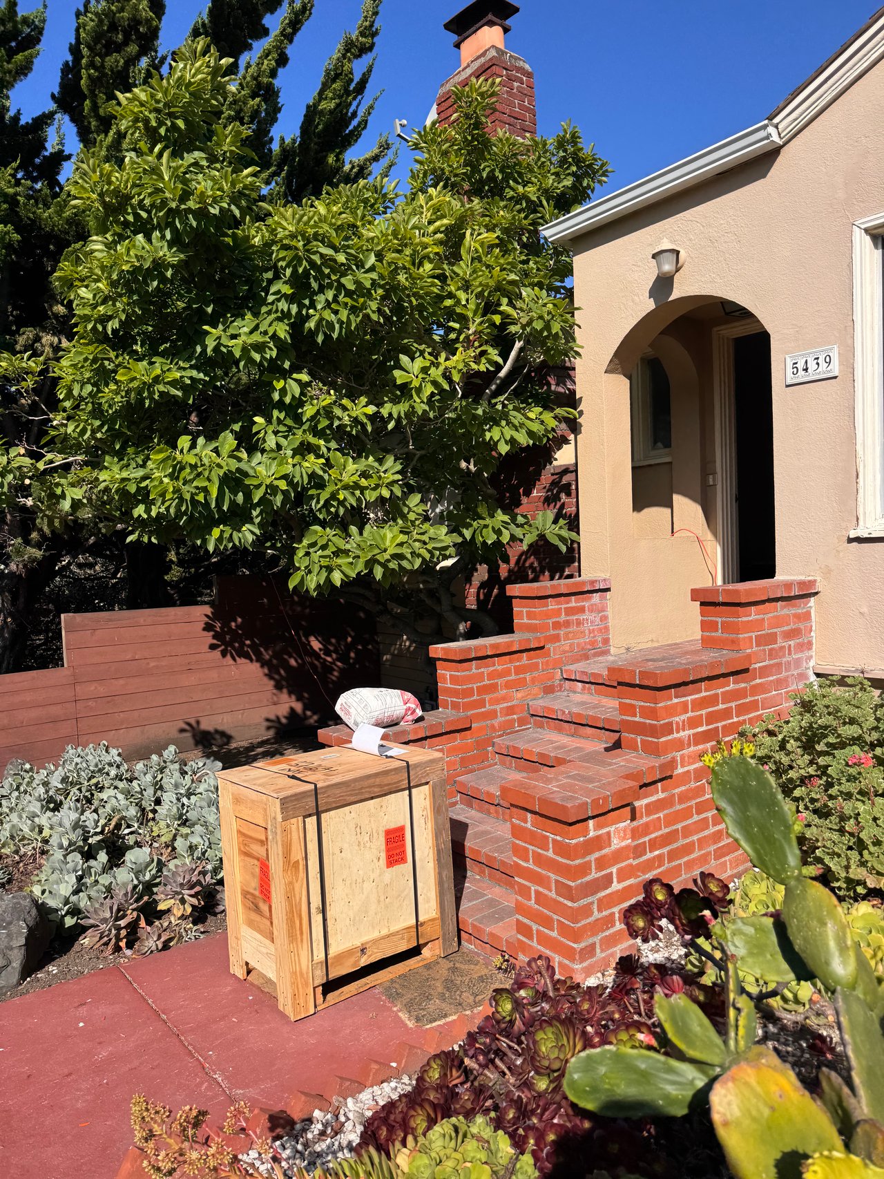 1940s home with brick steps and a large wooden box 