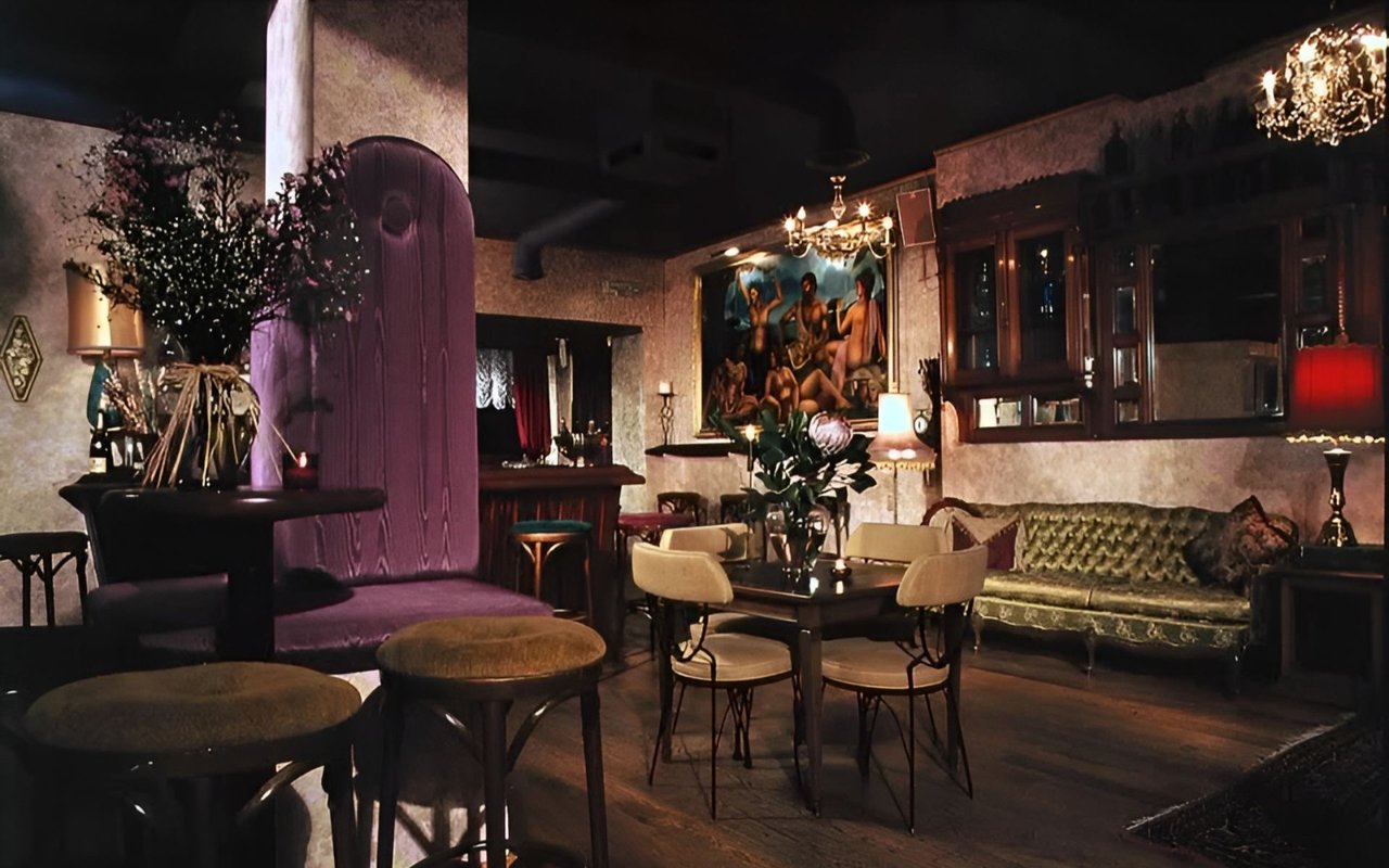 Club Lua lounge interior with purple seating, chandeliers, and a green tufted sofa.