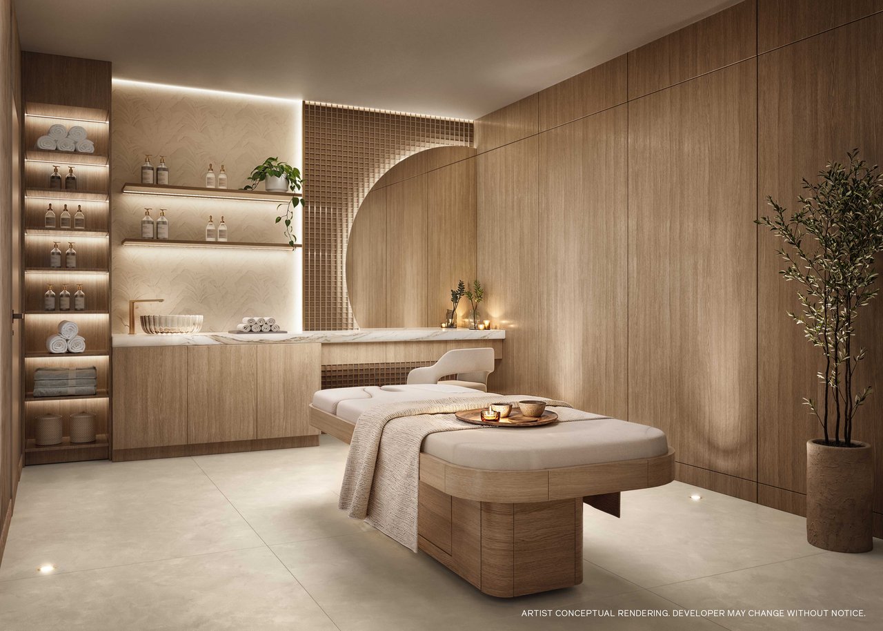 Spa treatment room with a padded massage table, illuminated shelves, and warm wood finishes.