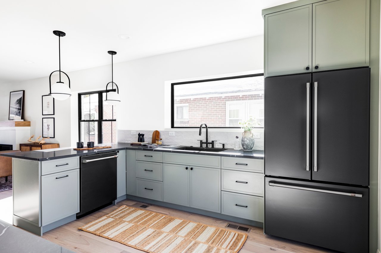 Bright kitchen opening up to the living room with black appliances and finishes