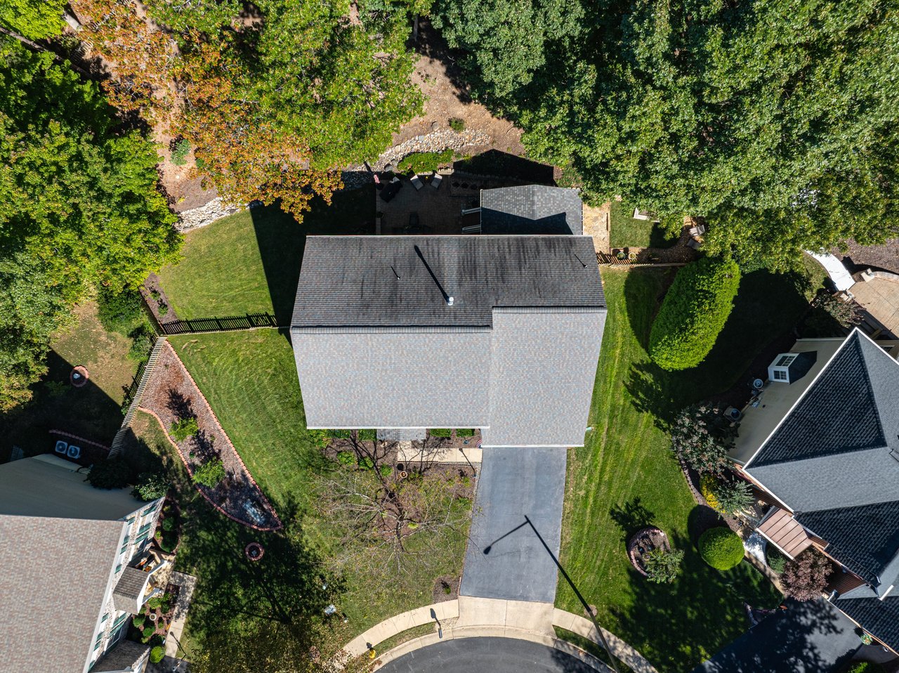 Aerial view of the home, driveway, landscaped yard, and rear patio.