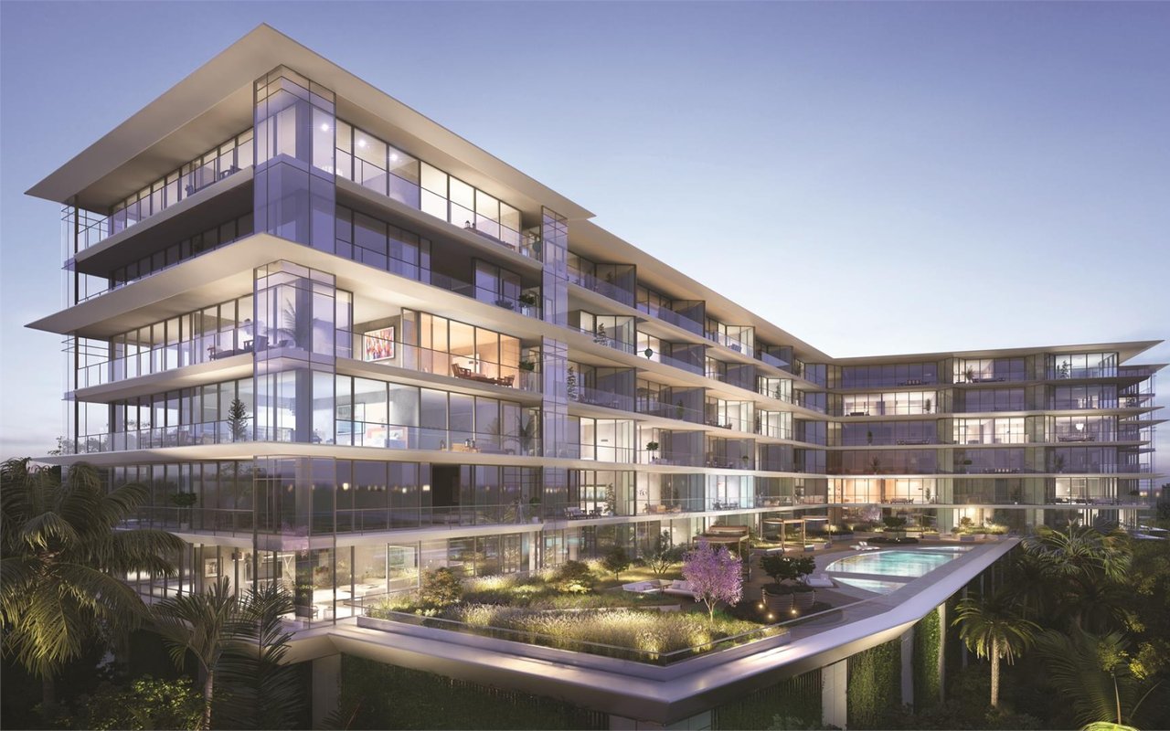 Modern residential building with glass balconies, landscaped terraces, and a pool at dusk.