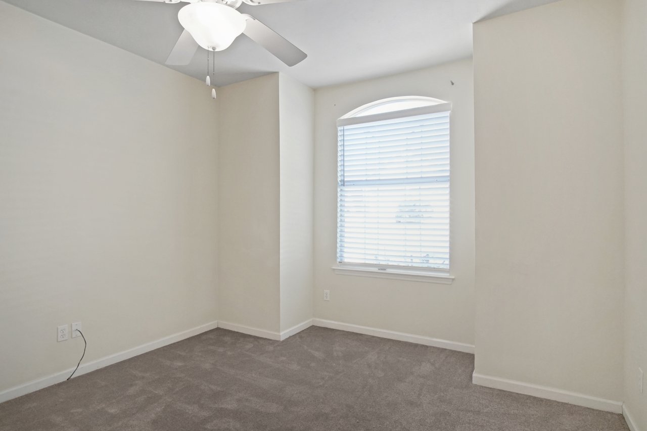 Bedroom at 5441 Hampton Hill Circle, Tallahassee, Florida 32311 with arched window, carpet flooring, and ceiling fan.