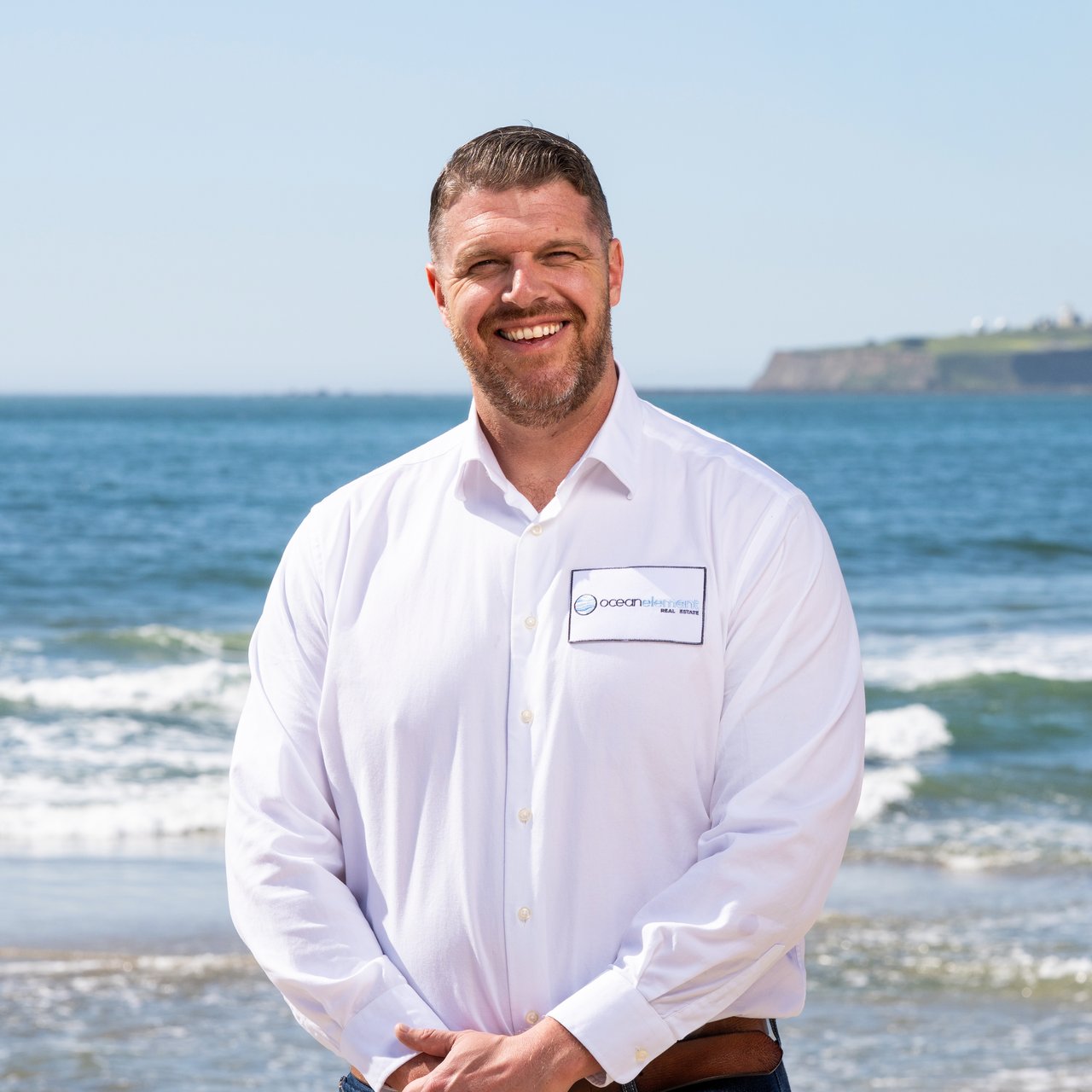 Brian Ely, Half Moon Bay real estate agent with Ocean Element Real Estate, standing on a Coastside beach with ocean views in San Mateo County