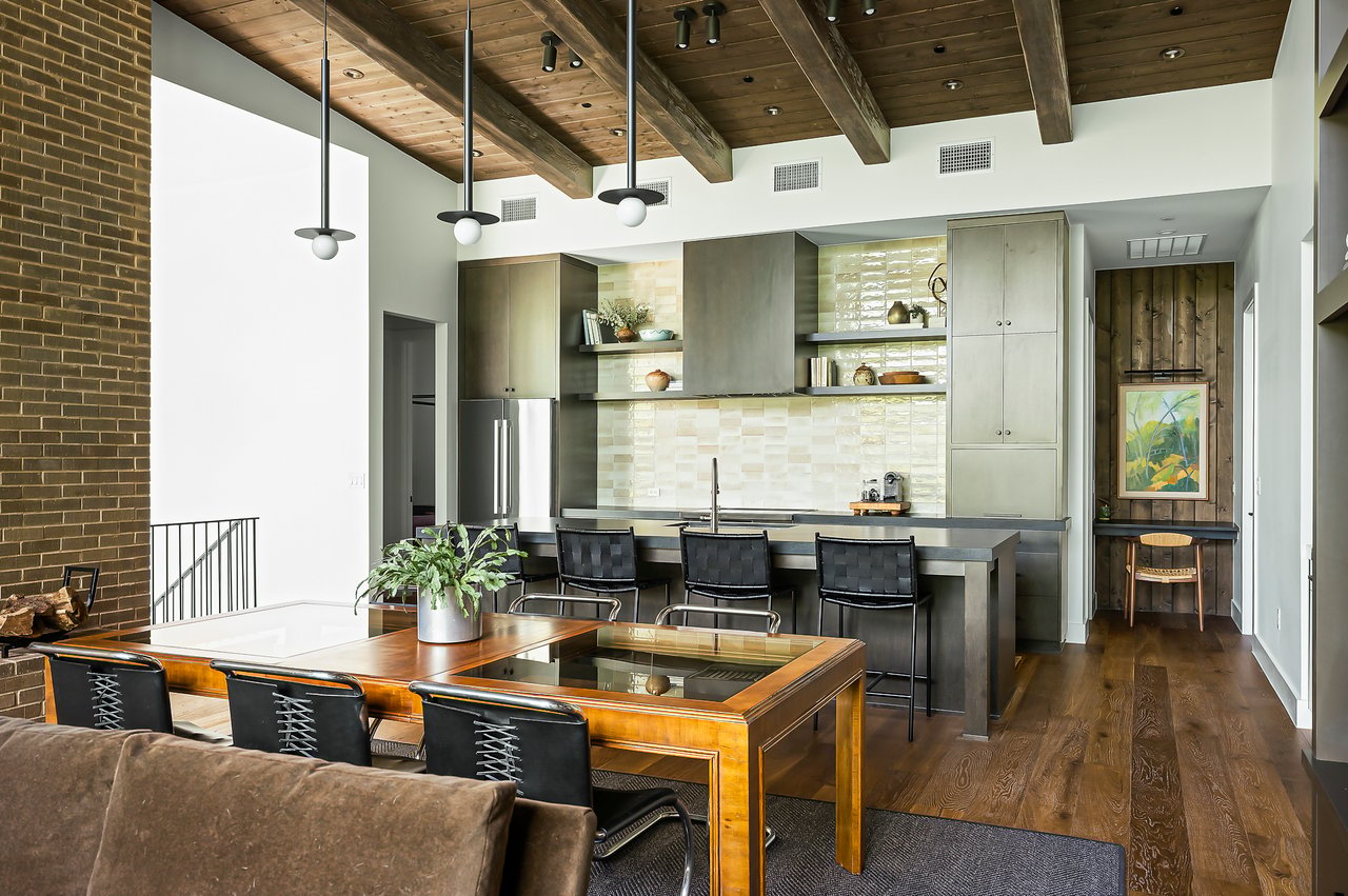 Kitchen and dining under exposed beams with island seating and Austin Wood Works custom cabinetry. Lake Austin waterfront at 2403 Big Horn Drive, Austin.