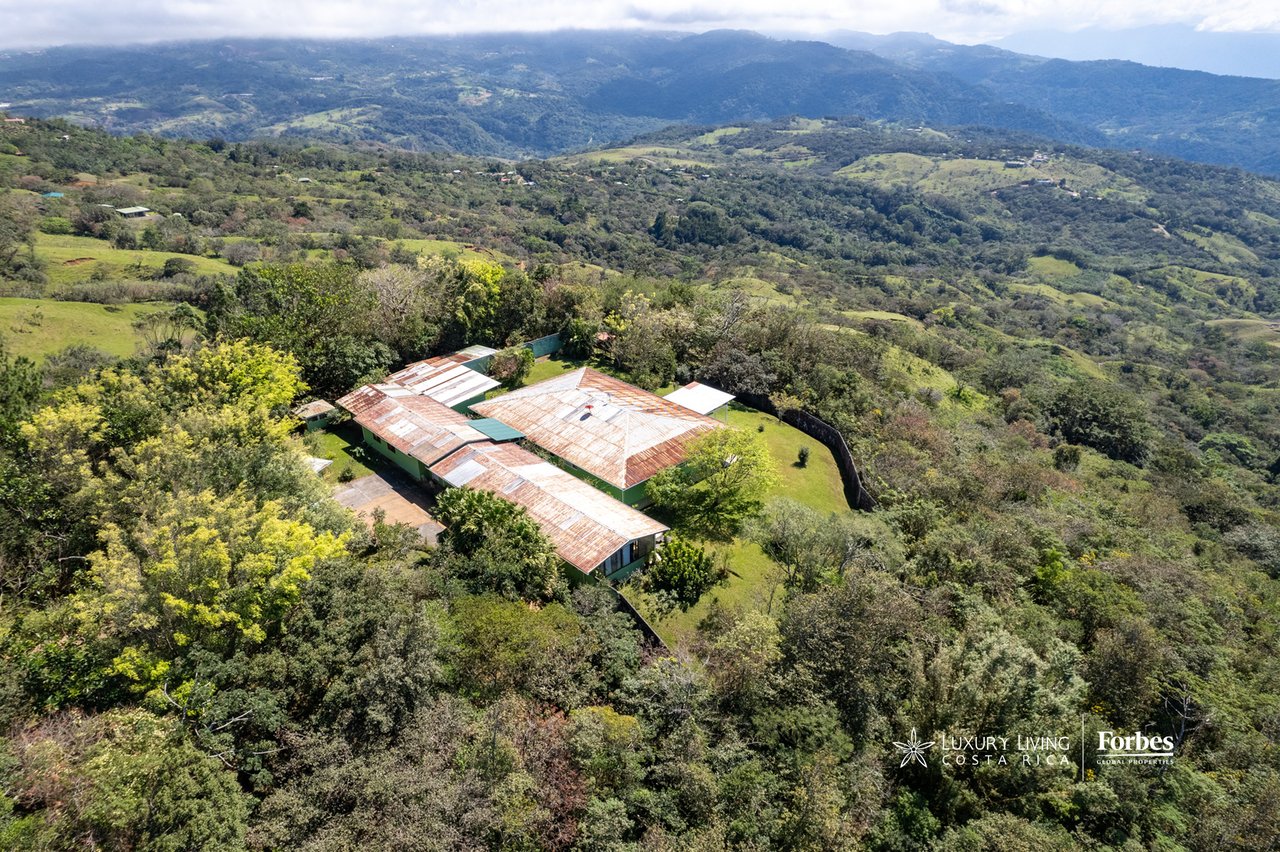 Aerial view of a mountain retreat amid green hills, with distant ridges stretching across the background.