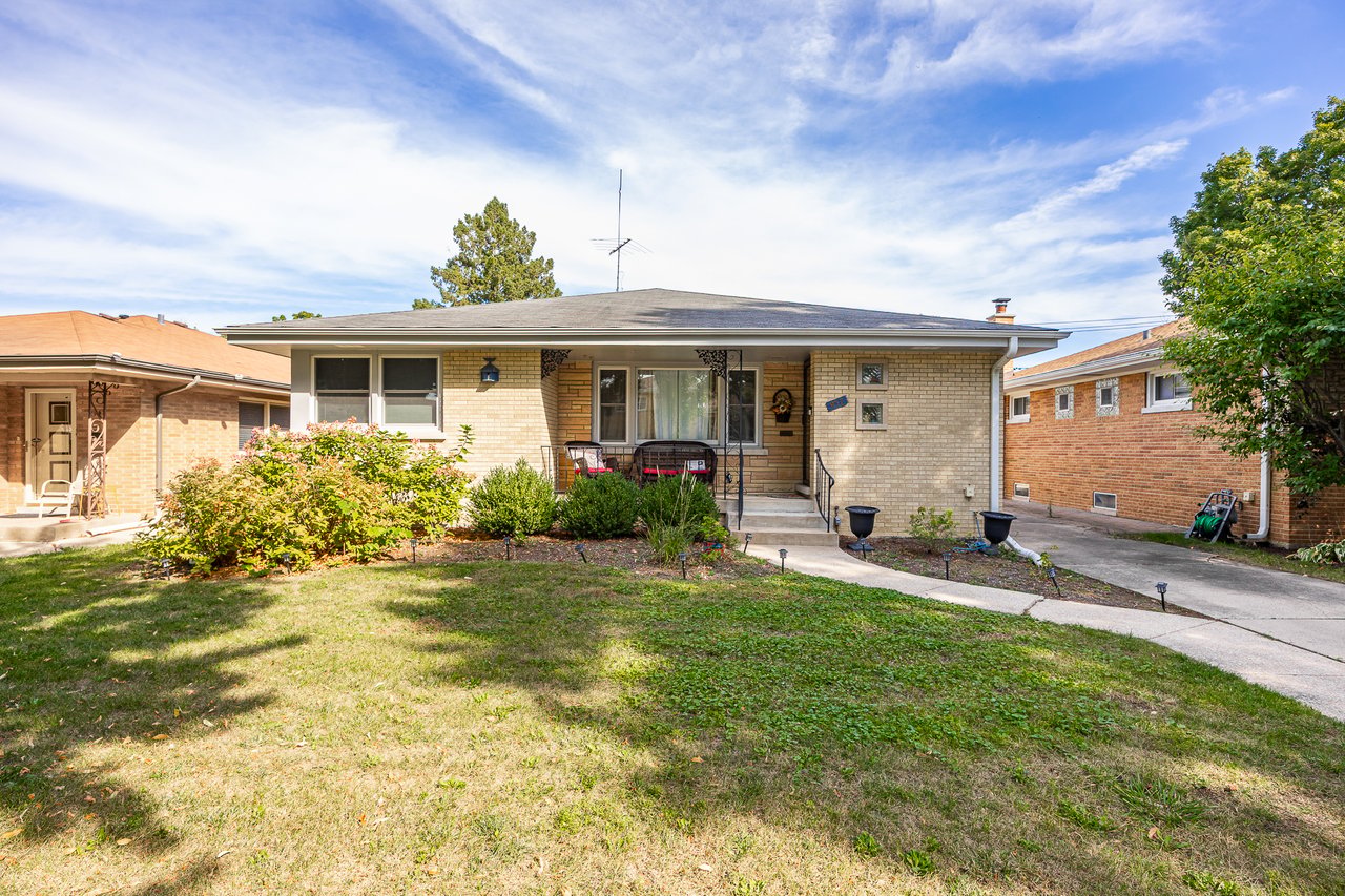 Single-story brick home with a covered entry, front lawn, and neighboring houses.