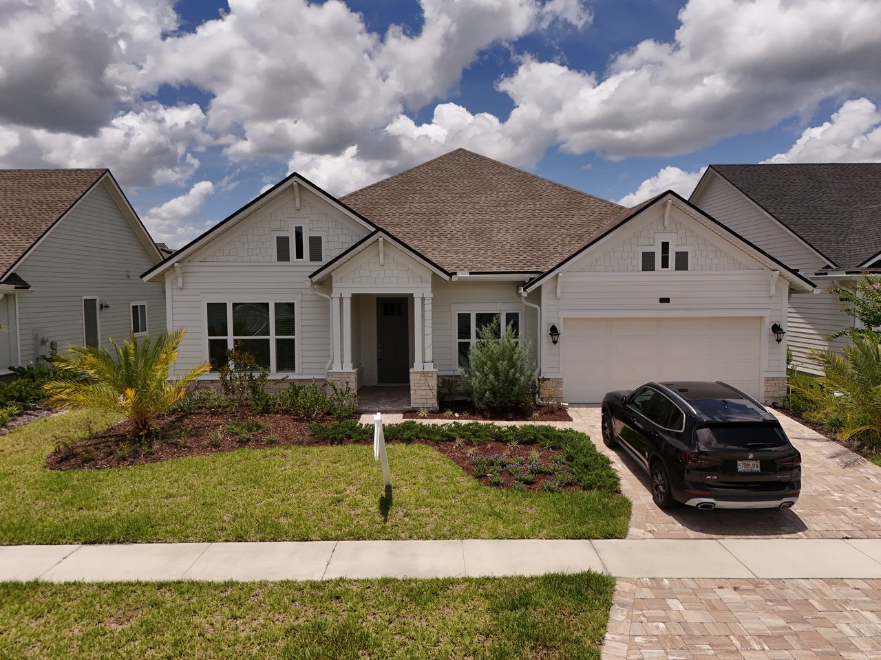 Single-story home with a covered entry, two-car garage, landscaped lawn, and SUV in the driveway.