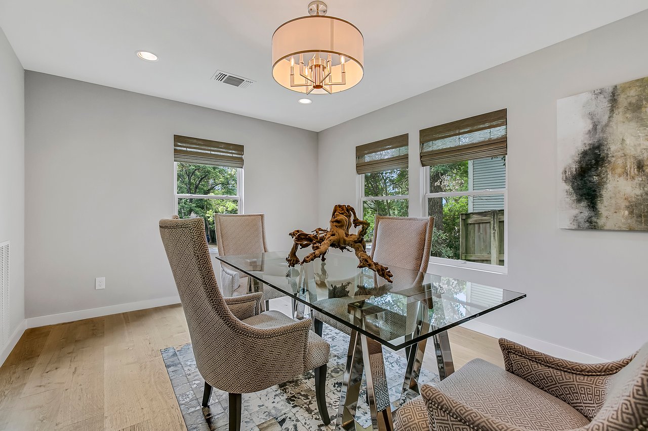 Formal dining room at 1004 Maufrais Street in Clarksville (Old West Austin), Austin, TX, featuring a glass-top table, upholstered chairs, and wide-plank white oak floors beneath a drum chandelier.