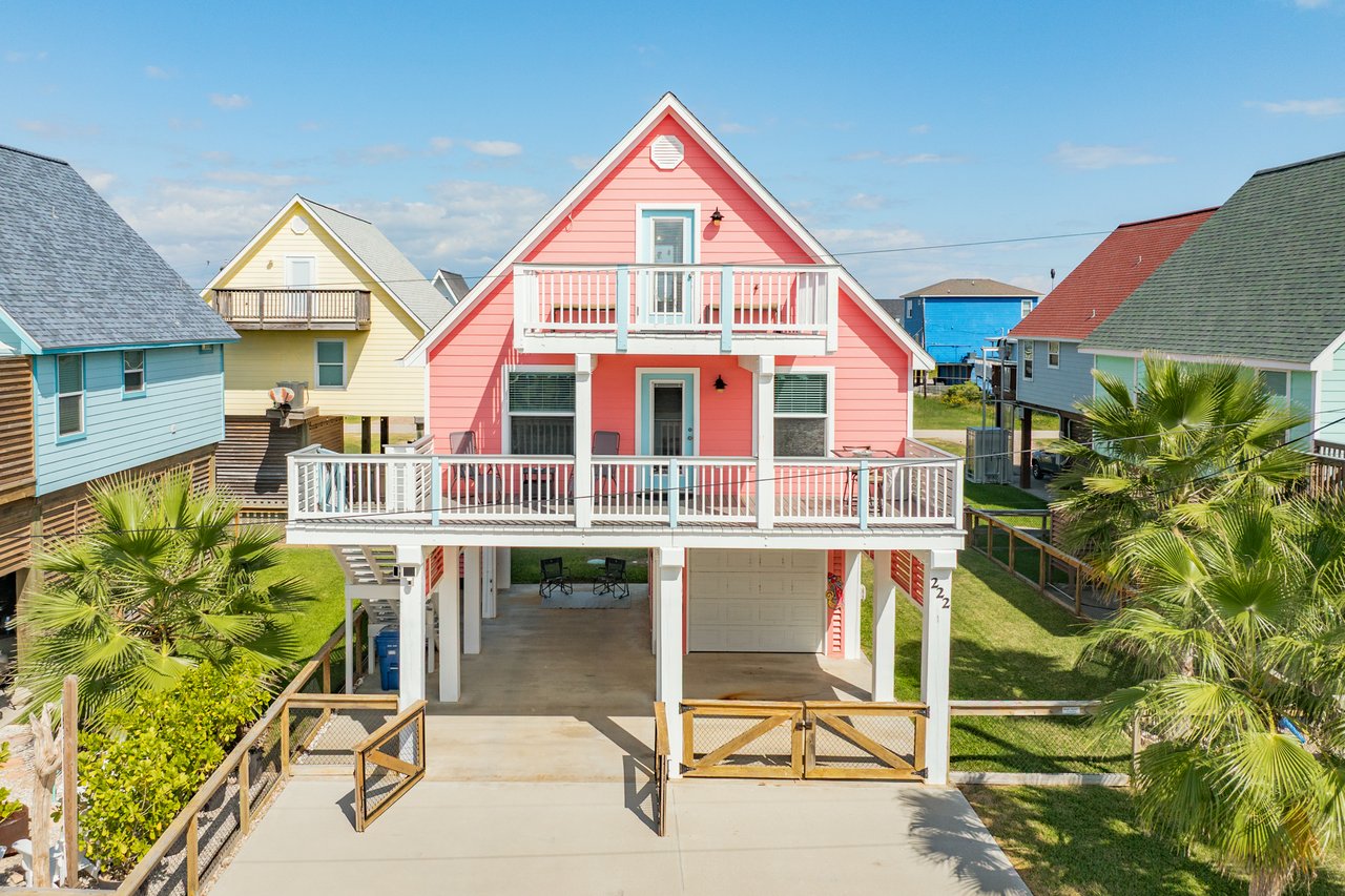 222 Sea Oats, Surfside Beach Texas, a coral color A-Frame beach house in Surfside, with white deck trim and fenced yard.