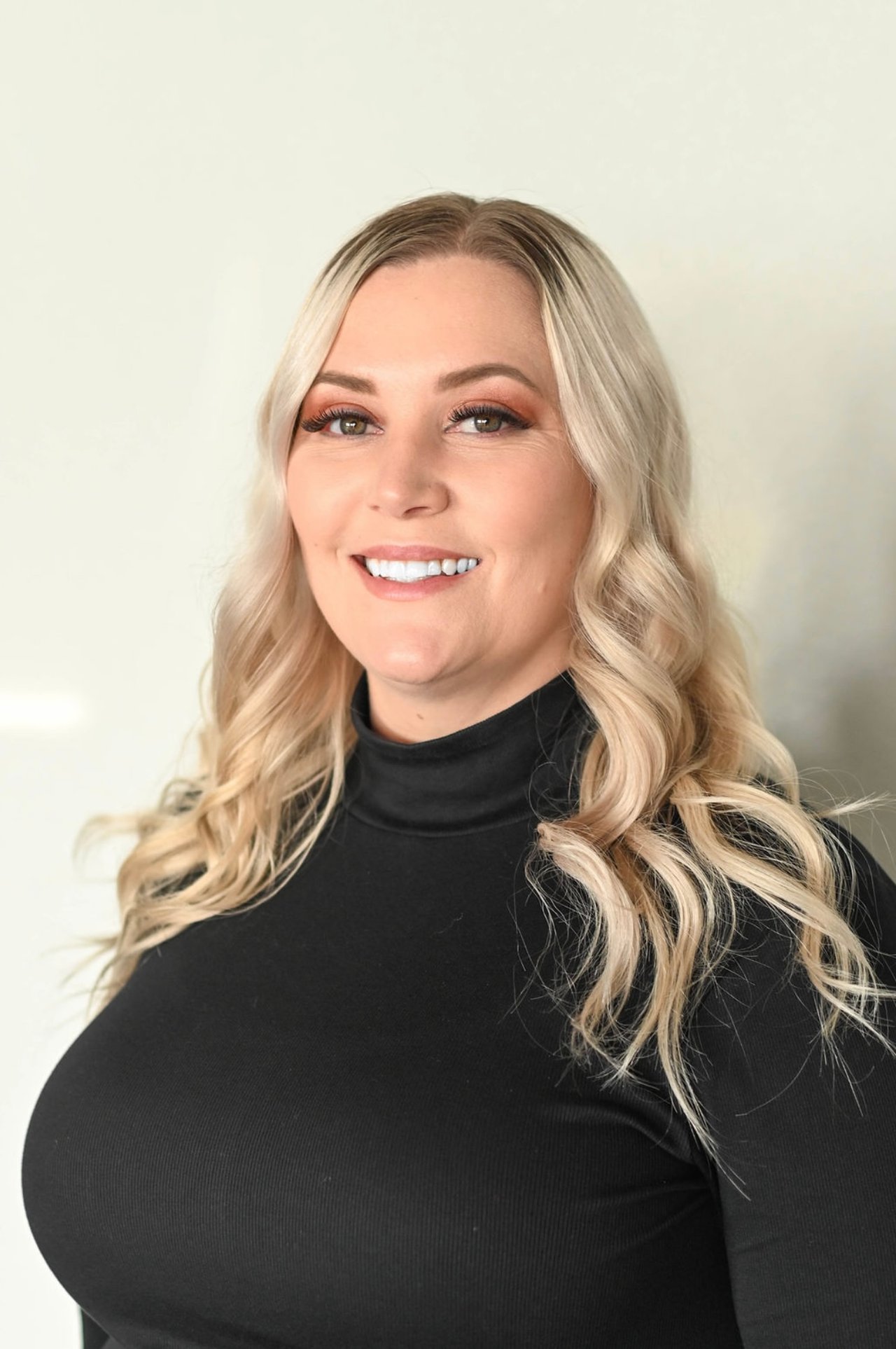Lindsay Tankersley smiling in a black top, with long wavy blonde hair.