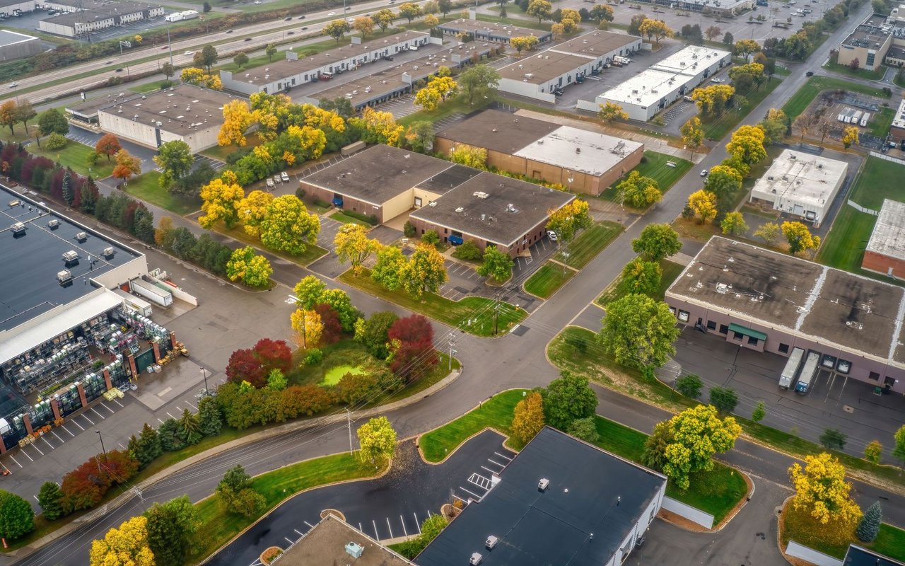 Aerial view of Plymouth commercial buildings and parking lots among autumn trees.