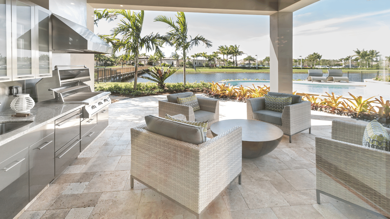 Outdoor kitchen with stainless steel appliances, lounge seating, and lakefront views in homes for sale in Gainesville FL. Gainesville FL realtor Anna Olcese.
