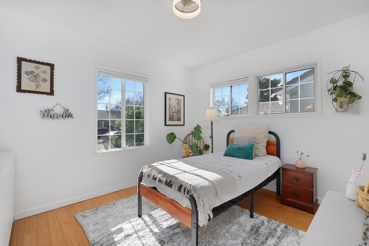Bright guest bedroom with twin bed, wood floors, and corner windows at 17049 Baltar Street in Lake Balboa
