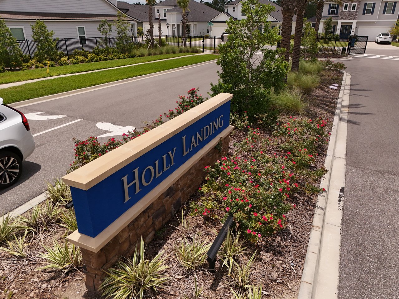 Holly Landing entrance sign beside a landscaped street with homes in the background.