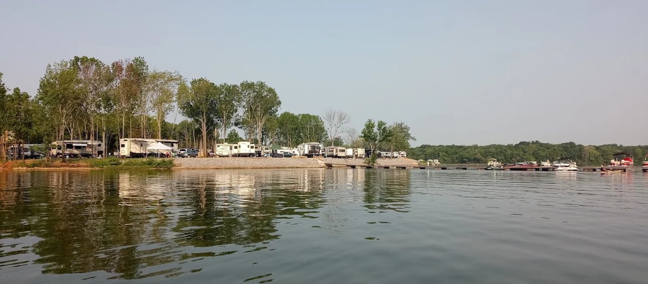 Lakefront campground with recreational vehicles along the wooded shore and boats at the docks.