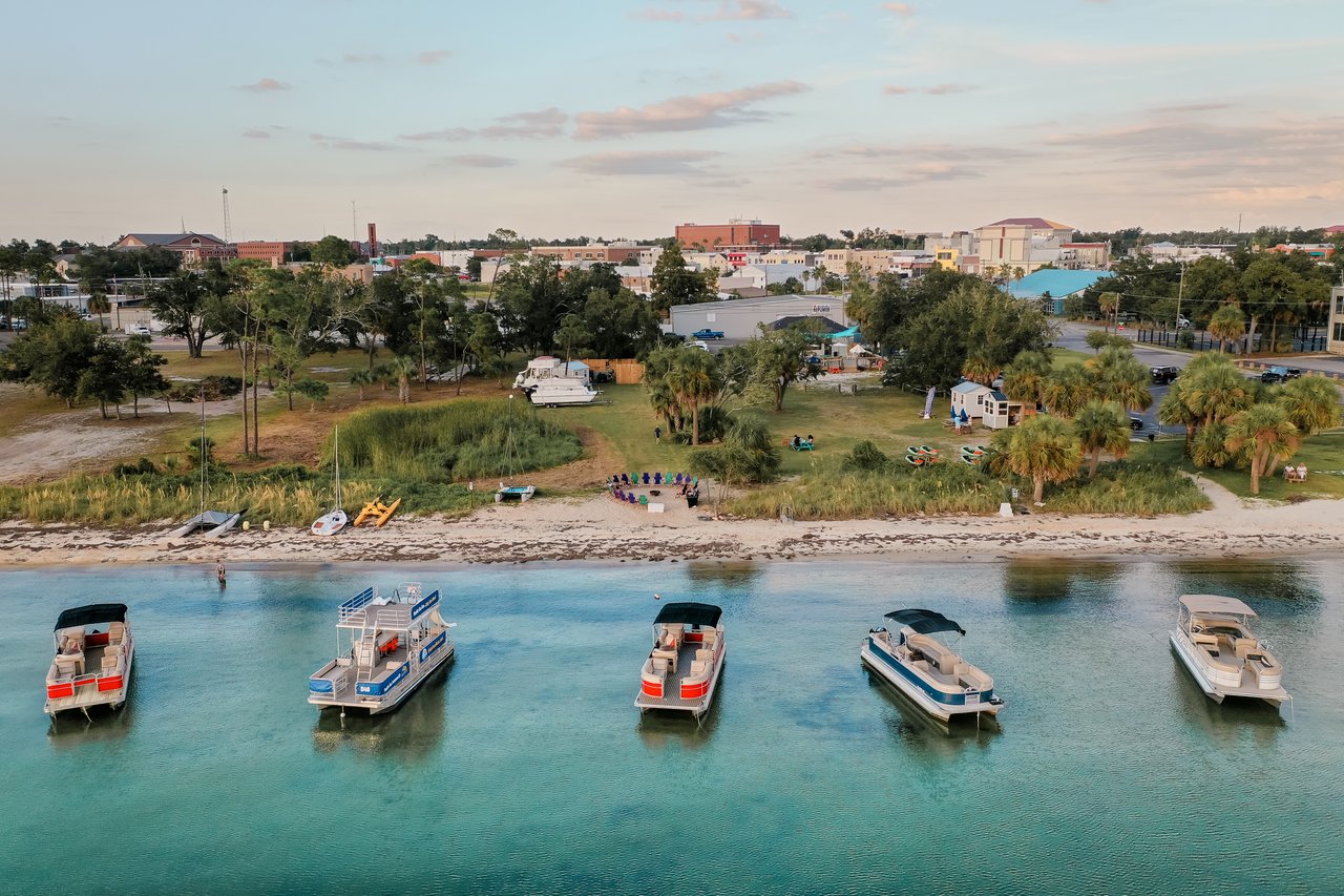 Aerial view of a waterfront in Panama City, with boats, sandy shore, and low-rise buildings.