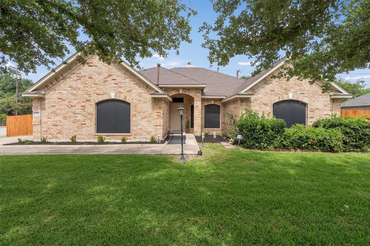 Single-story brick property with arched dark windows, a recessed entry, and a broad green lawn.