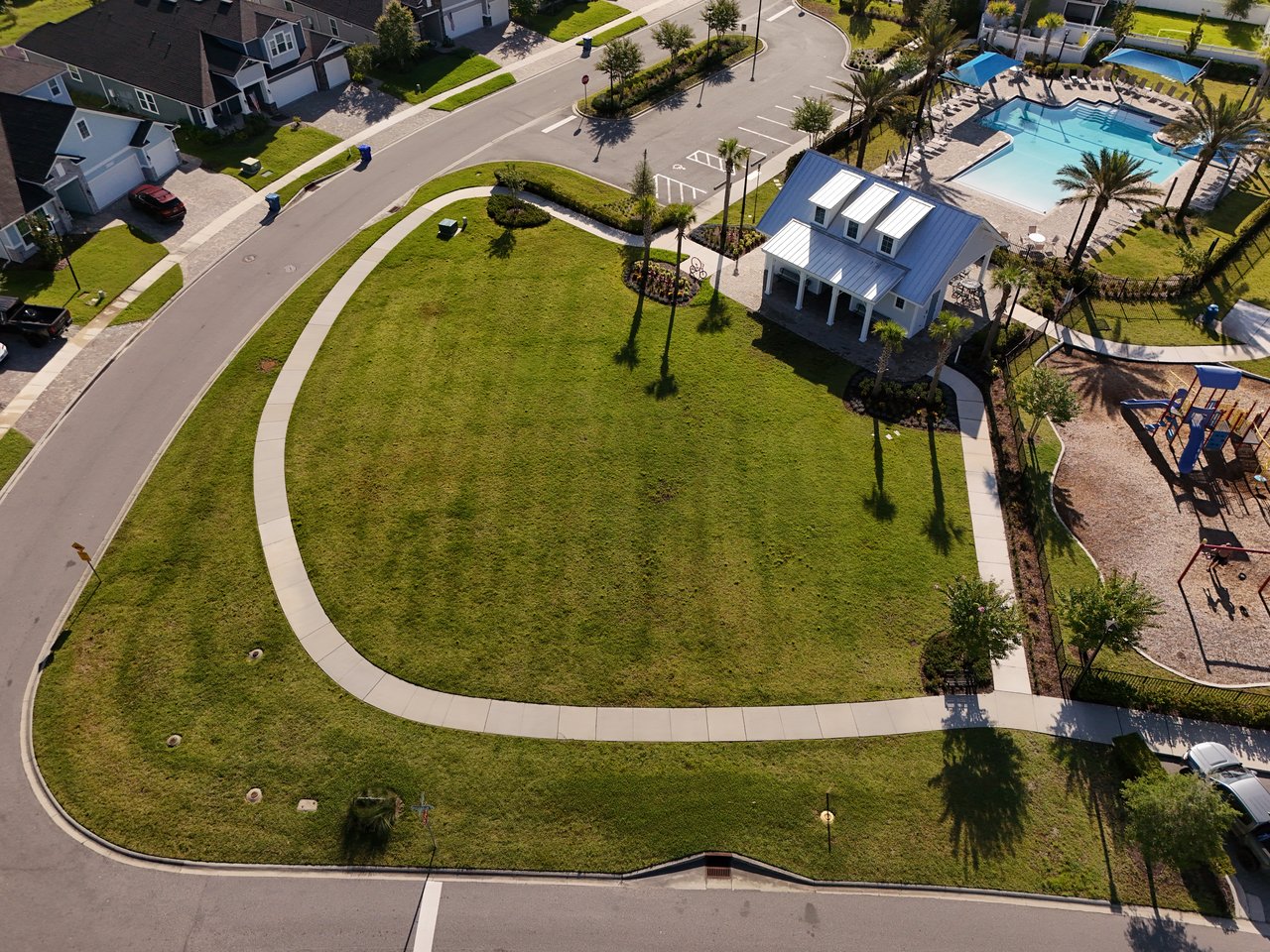 Aerial view of a neighborhood green space with a clubhouse, swimming pool, and playground.