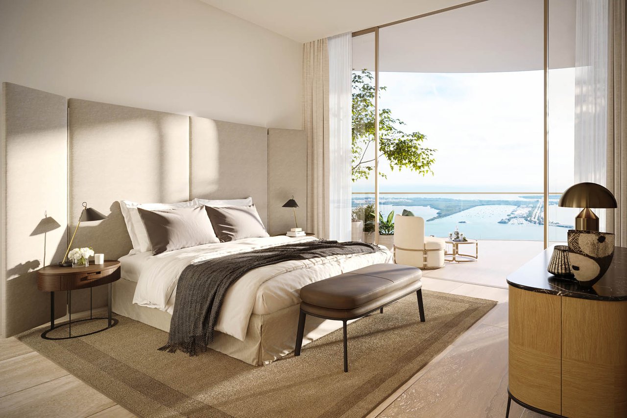 Staged bedroom with a king bed and floor-to-ceiling windows overlooking the water.