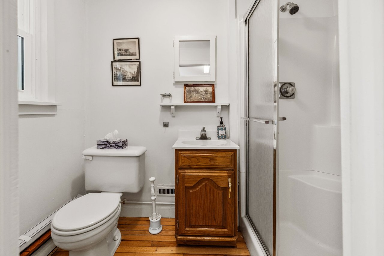 Bathroom with a wood vanity, hardwood floor, and frosted-glass shower door.
