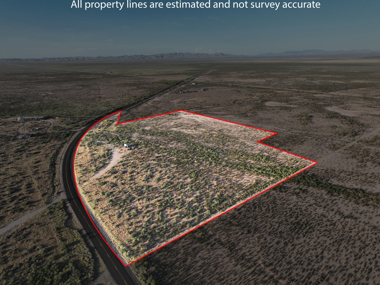 Aerial view of vacant desert land outlined in red beside a paved road.