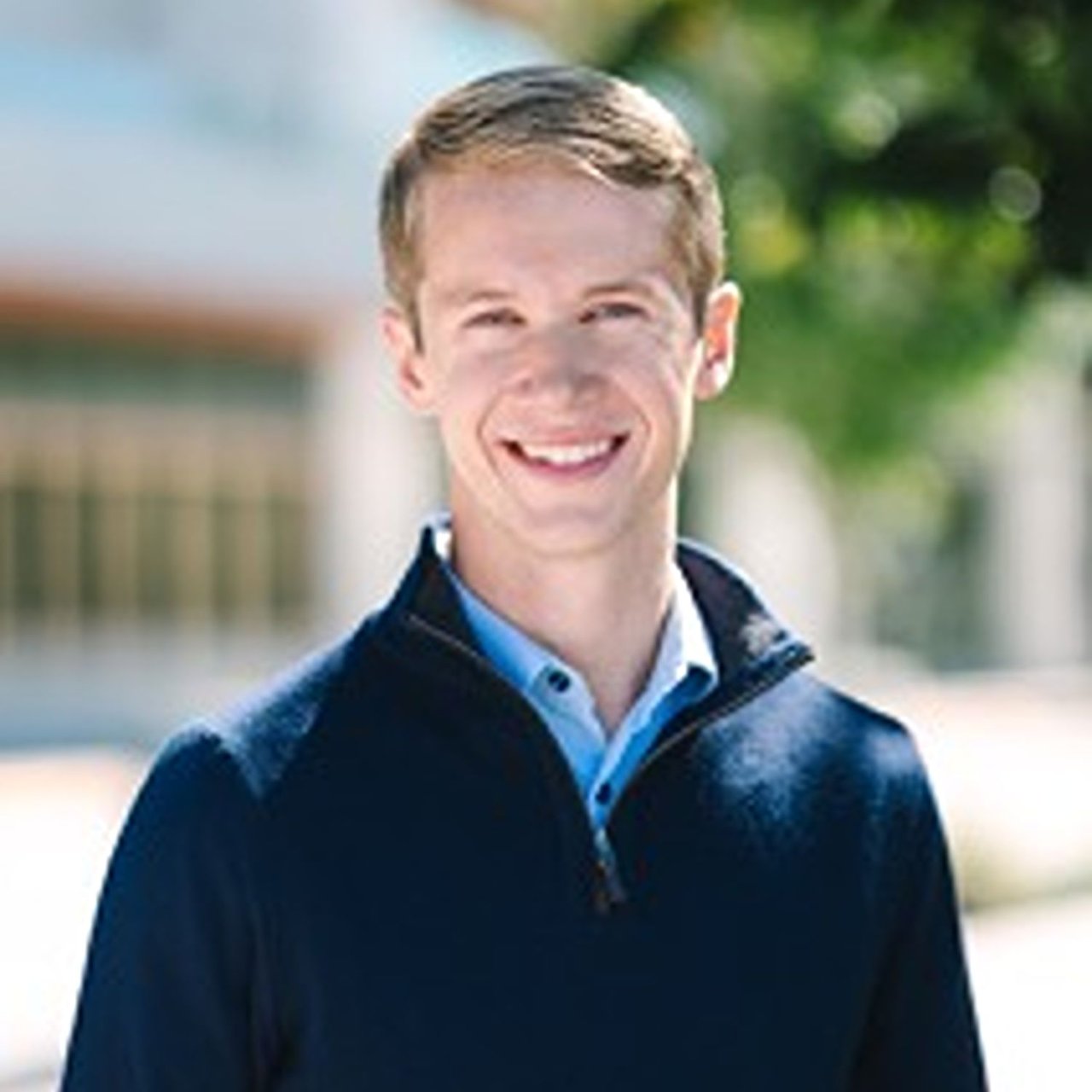 Jeremiah Hawkins smiling in a navy sweater and blue collared shirt.
