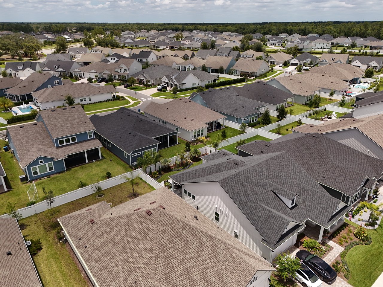 Aerial view of a neighborhood with closely spaced homes and fenced yards.