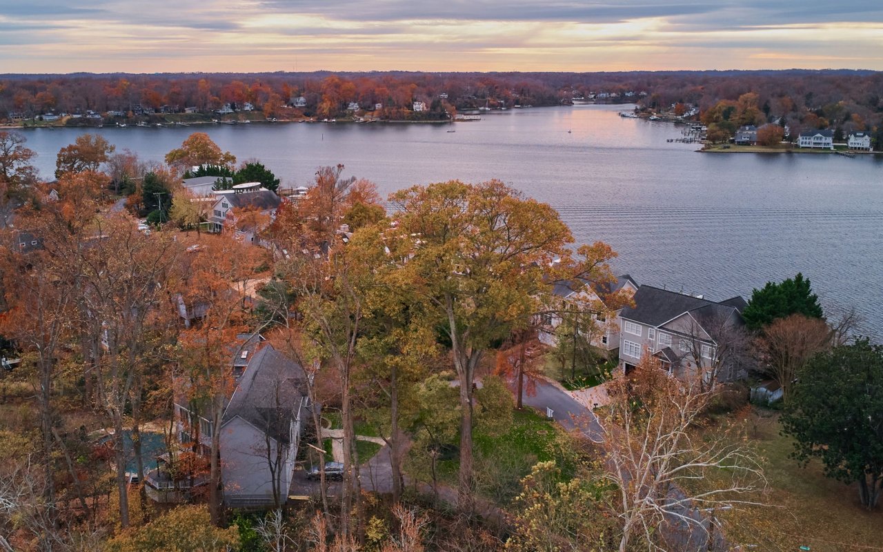 Aerial view of autumn-colored homes along a lake at sunset.