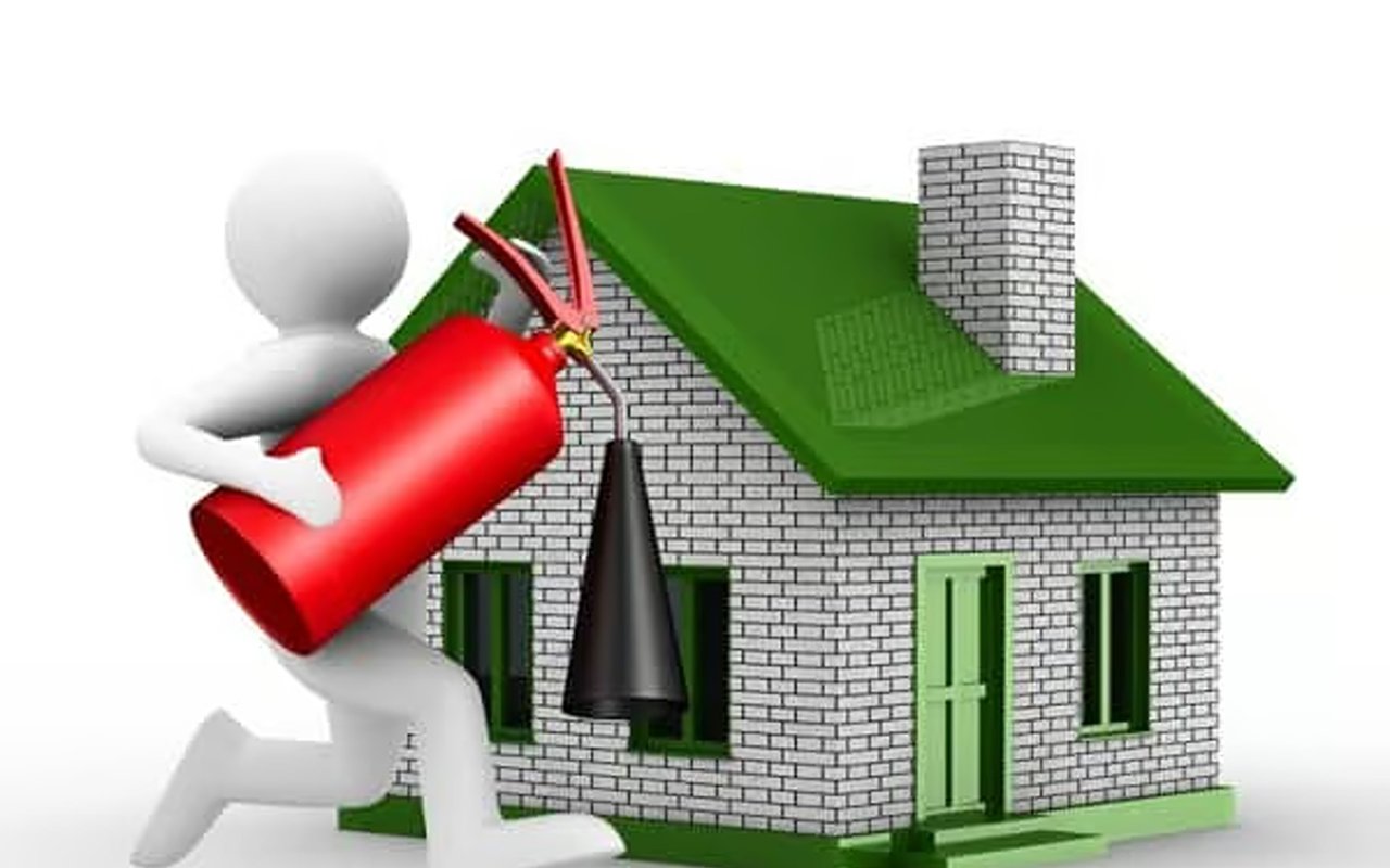 Figure holding a fire extinguisher beside a brick house with a green roof.