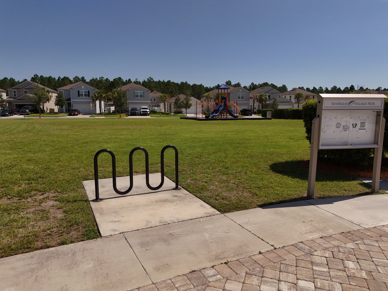 Silverleaf Village community green with a playground, bike rack, and HOA information board.