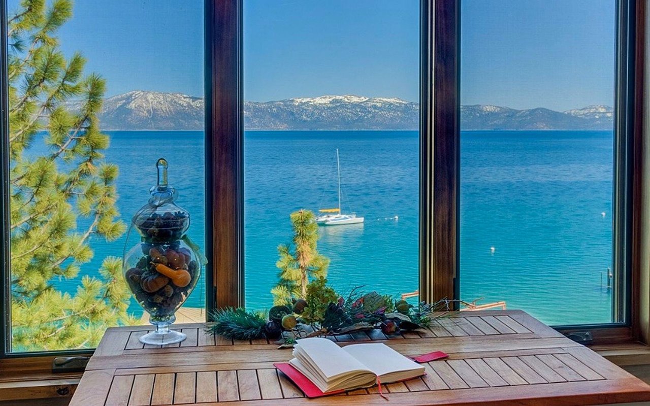 Lake and snow-dusted mountain views through large windows, with a sailboat offshore.