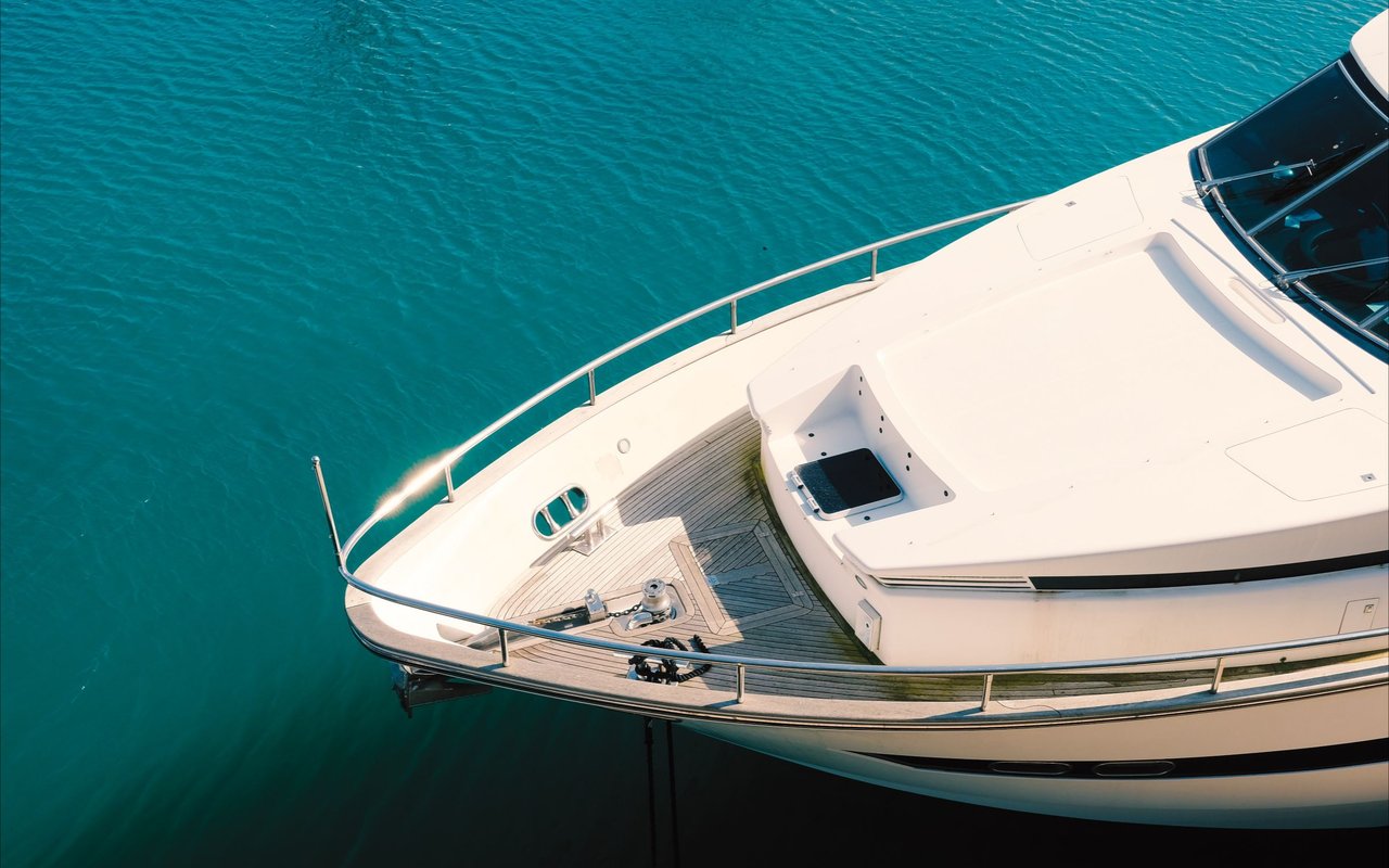 White yacht with a teak bow deck floating on turquoise water