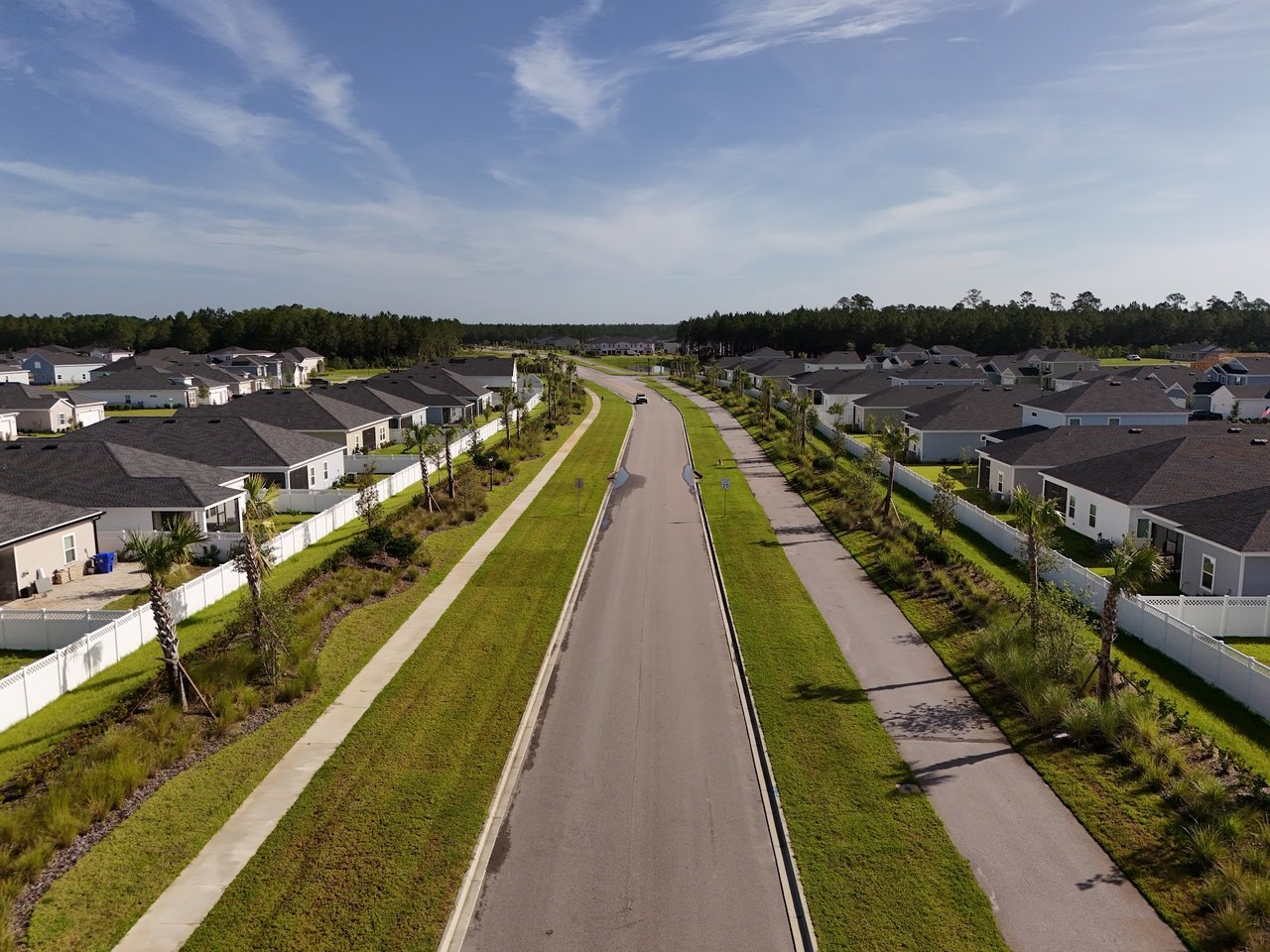 Aerial view of Silver Falls homes along a landscaped street with sidewalks and white fences.