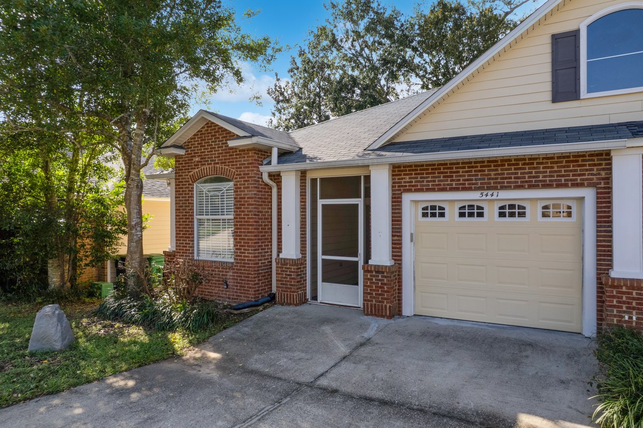 Front exterior of 5441 Hampton Hill Circle, Tallahassee, Florida 32311 showing brick façade, screened entry, and single-car garage.