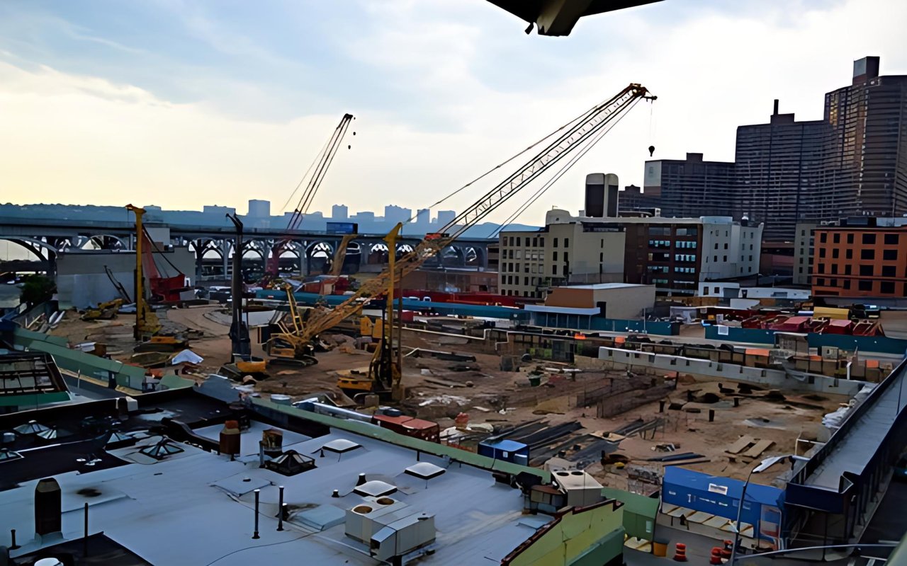 Urban construction site with cranes, a bridge, and high-rise buildings.