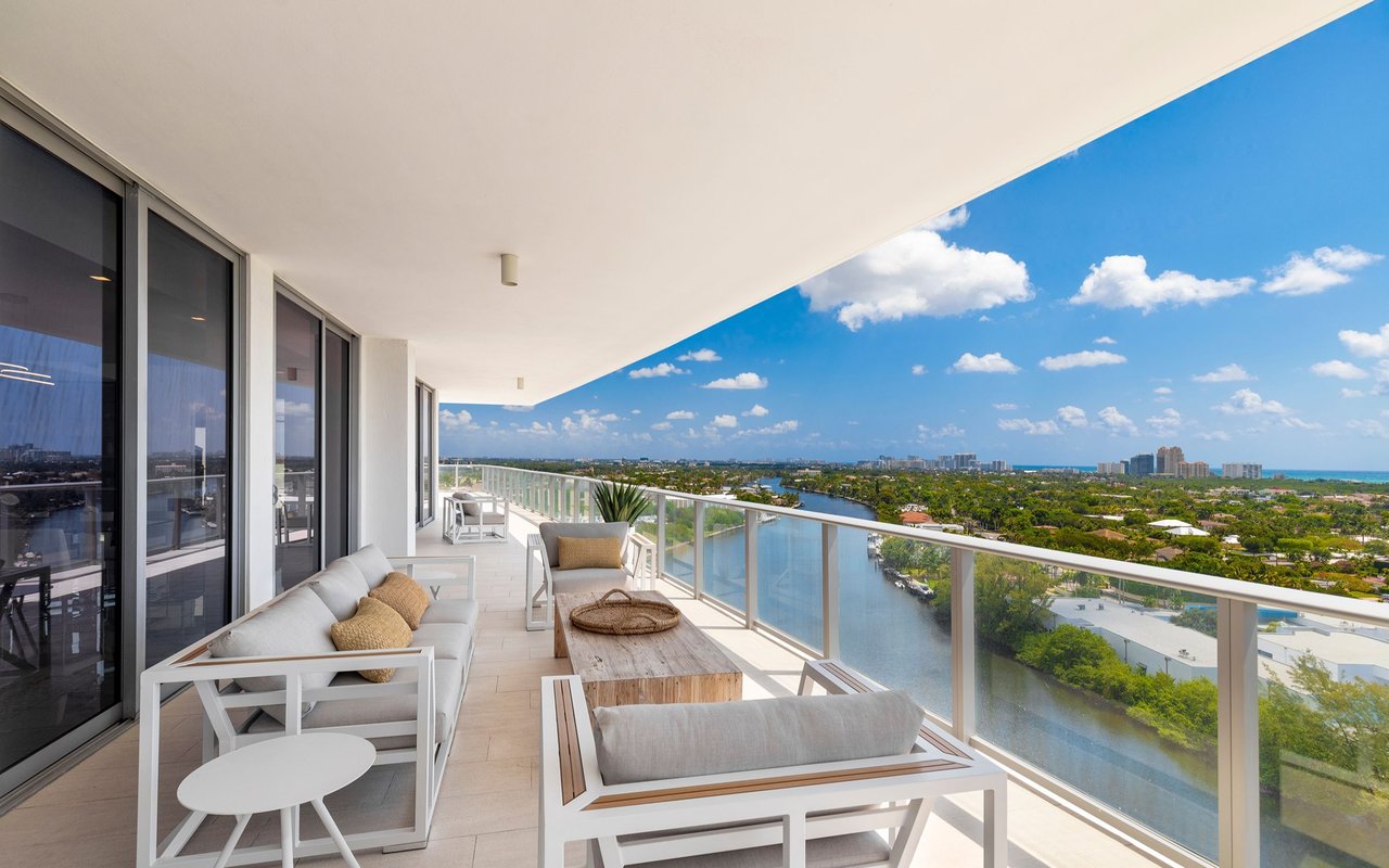 Furnished condo balcony overlooking a waterway and distant coastal skyline.