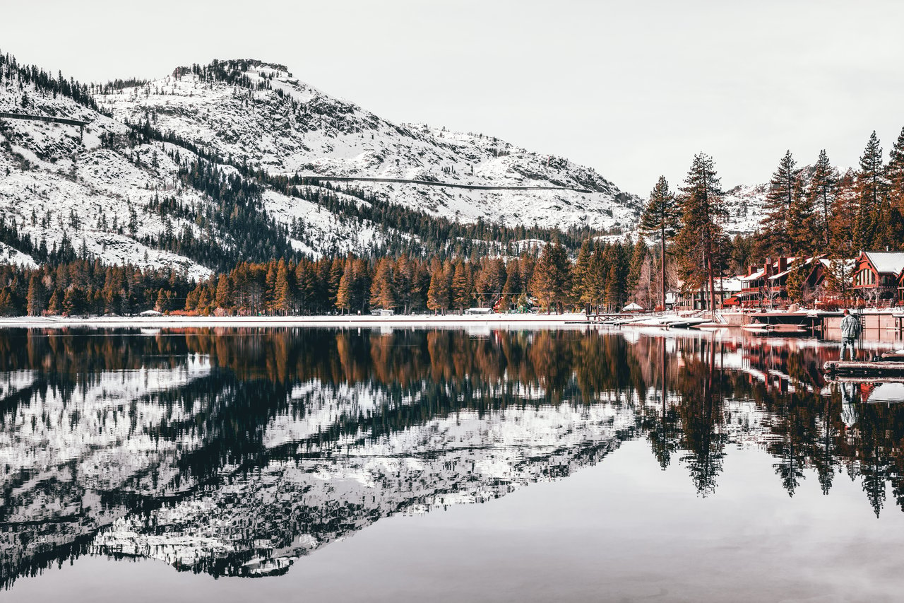 Snow-covered Truckee neighborhood with cozy mountain homes, tall pine trees, and a breathtaking winter landscape, ideal for winter living.