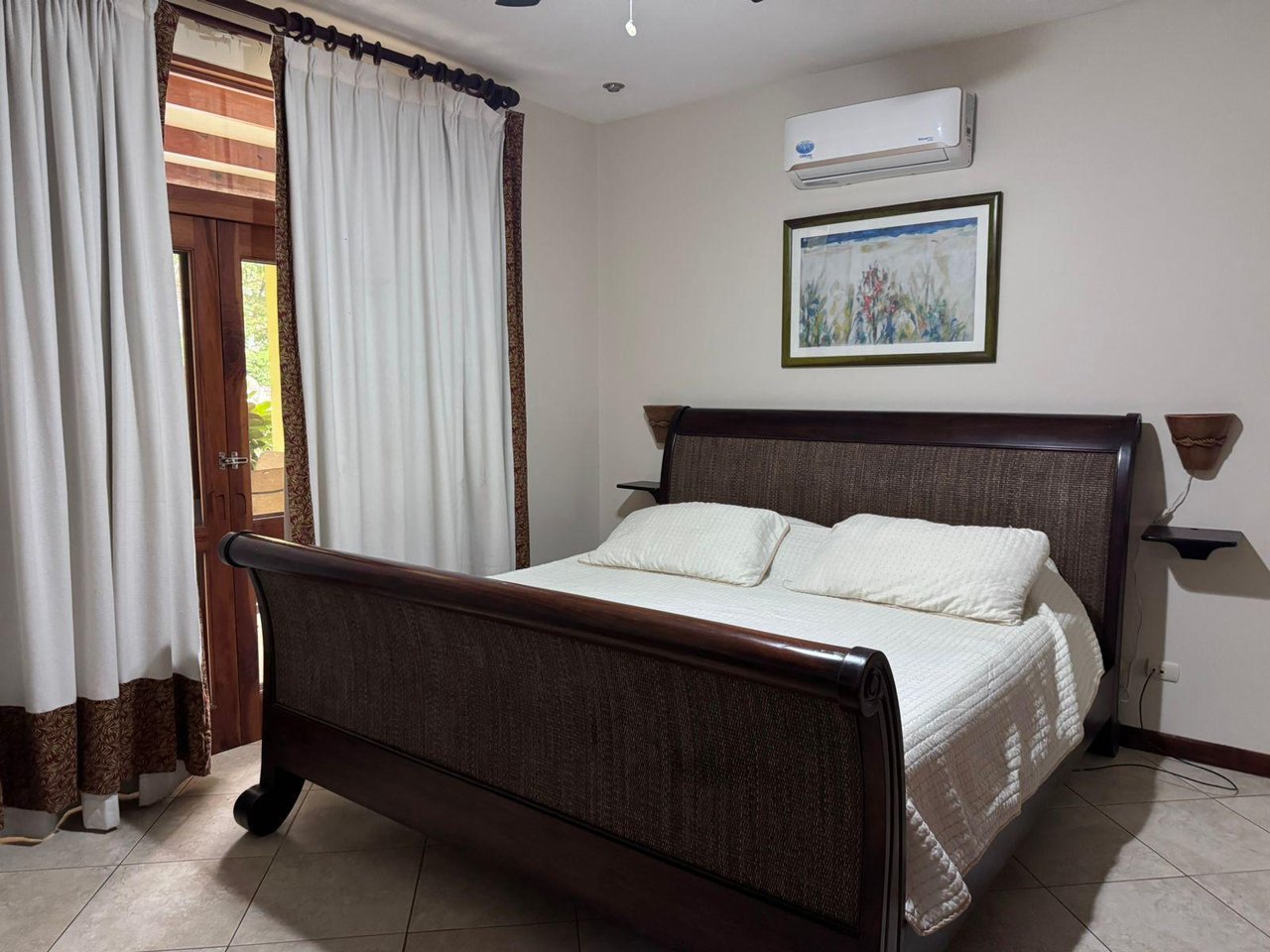 Bedroom with a dark wood bed, white bedding, and a curtained glass door beside it.