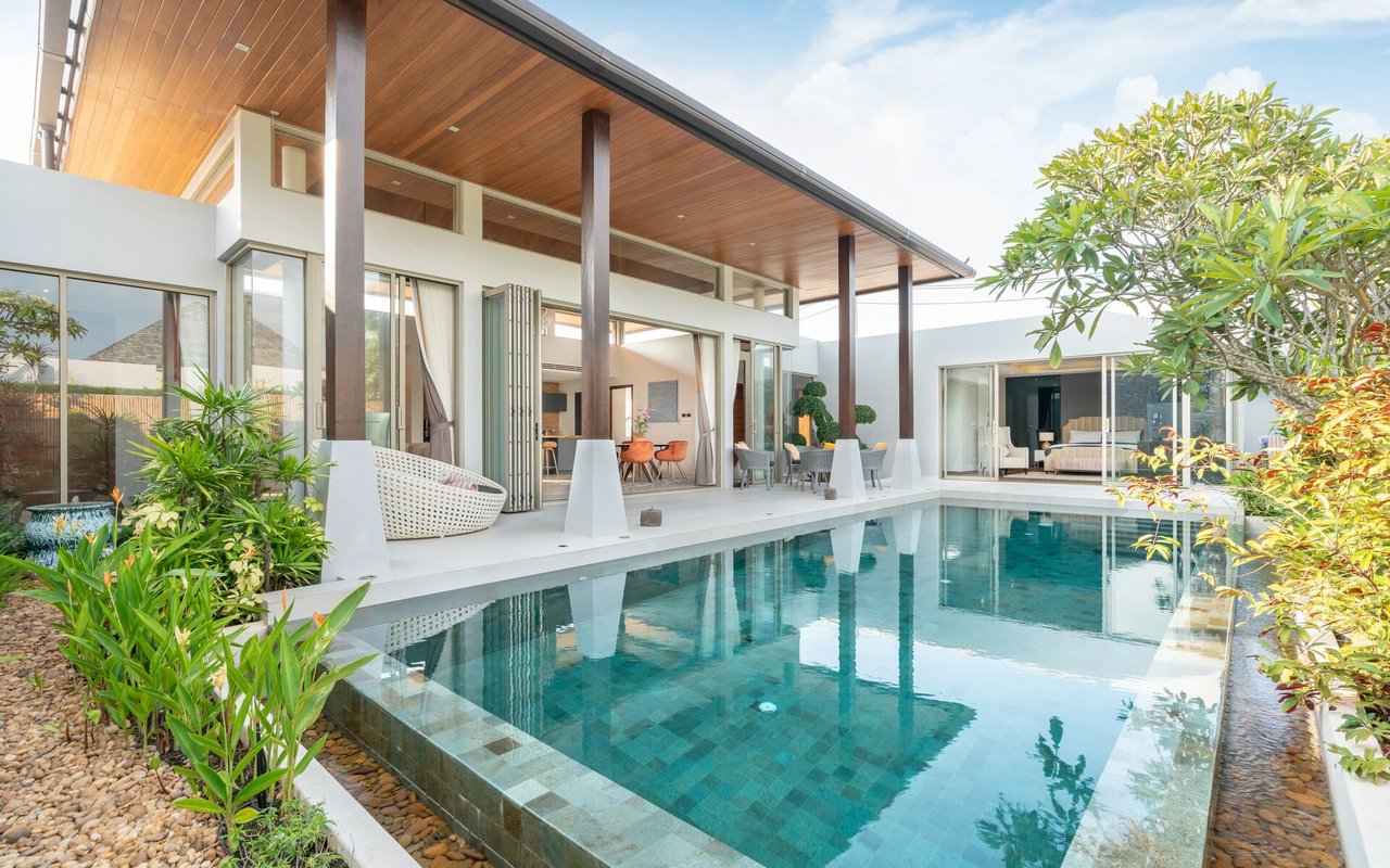 Modern white home with a wood-paneled roof and a landscaped swimming pool.